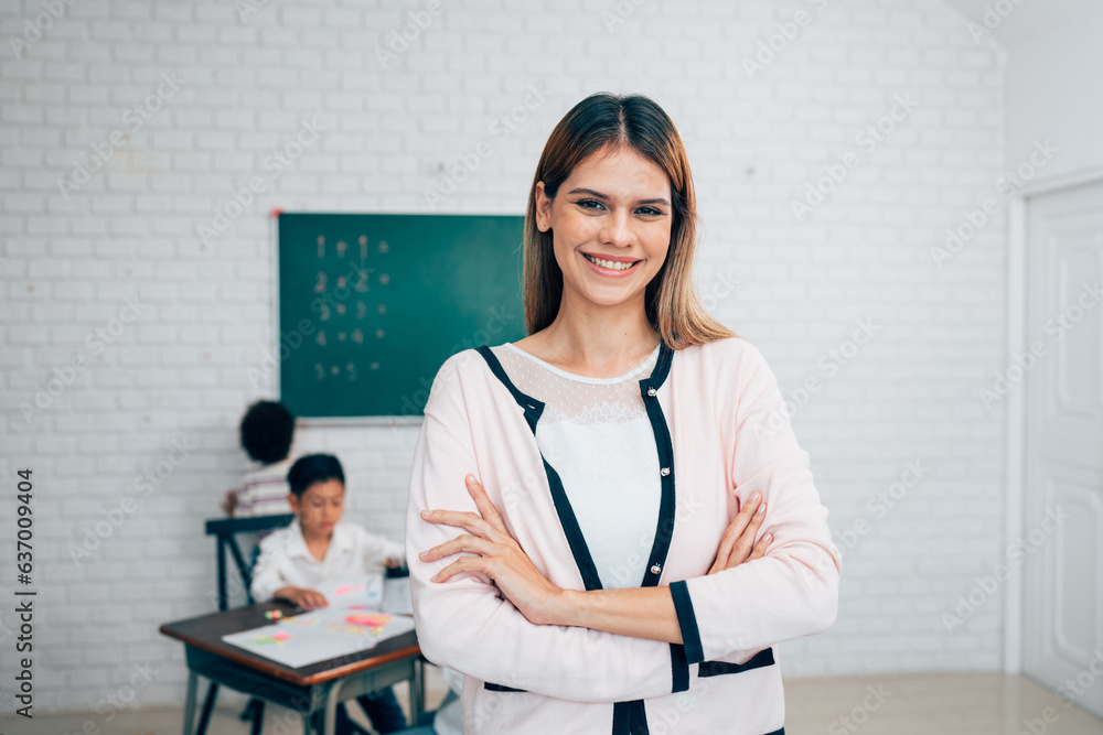Portrait of smiling female teacher looking at camera while posing confidently standing with arms crossed in school classroom, copy space. Portrait of smiling female teacher looking at camera while posing confidently standing with arms crossed in school classroom, copy space.