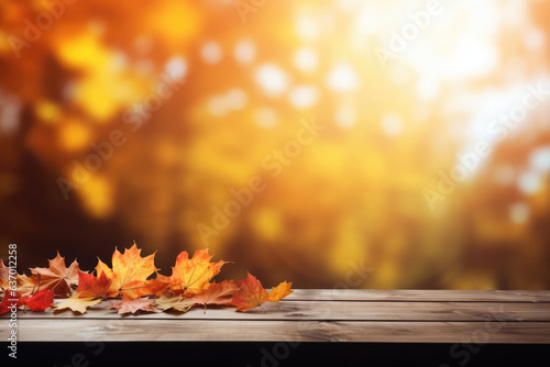 Wooden table with autumn leaves on bokeh background. Space for text or product display.