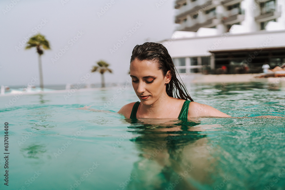Chica joven delgada posando en piscina de hotel de vacaciones en traje de baño