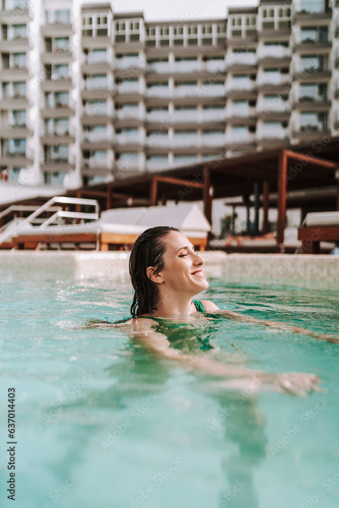 Chica joven delgada posando en piscina de hotel de vacaciones en traje de baño