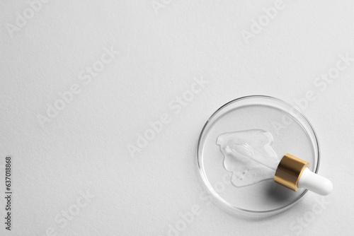 Petri dish with sample of cosmetic oil and pipette on white background, top view. Space for text