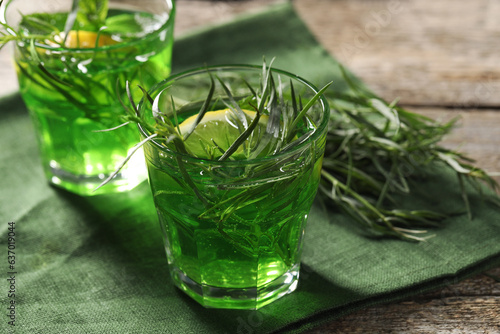 Glasses of refreshing tarragon drink with lemon slices on wooden table, closeup photo