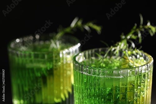 Glasses of homemade refreshing tarragon drink on black background, closeup