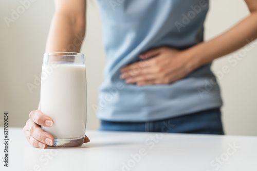 lactose intolerance concept. Woman holding a glass of milk and having a stomachache.