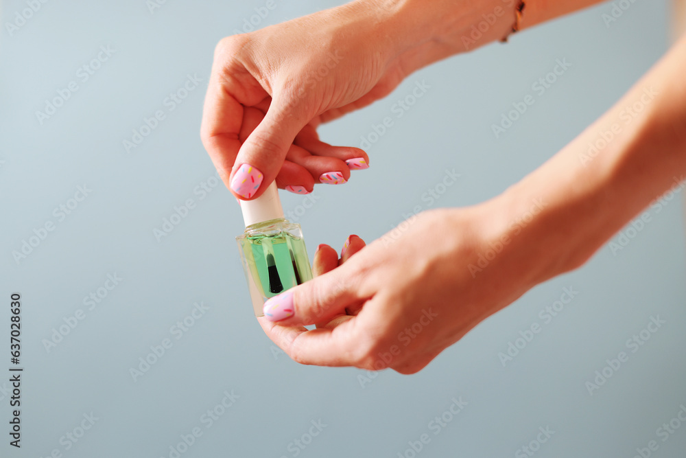 Naklejka premium Female hands with pink manicure hold cosmetic oil on fingers