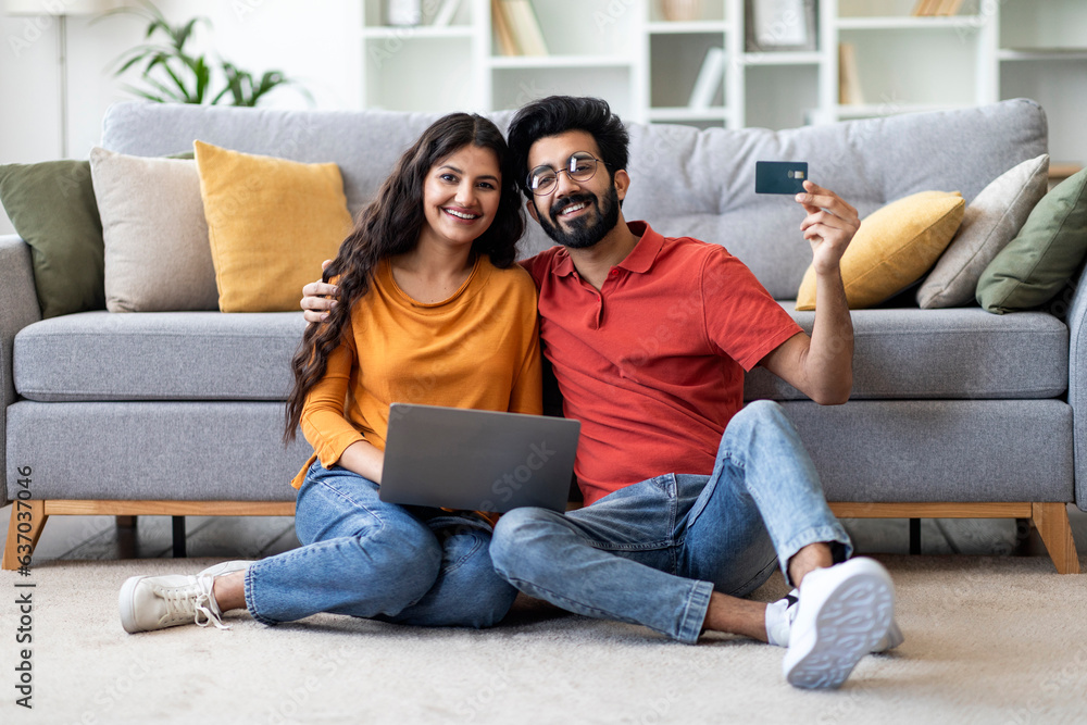 E-Commerce Concept. Smiling Young Indian Couple Holding Laptop And Showing Credit Card