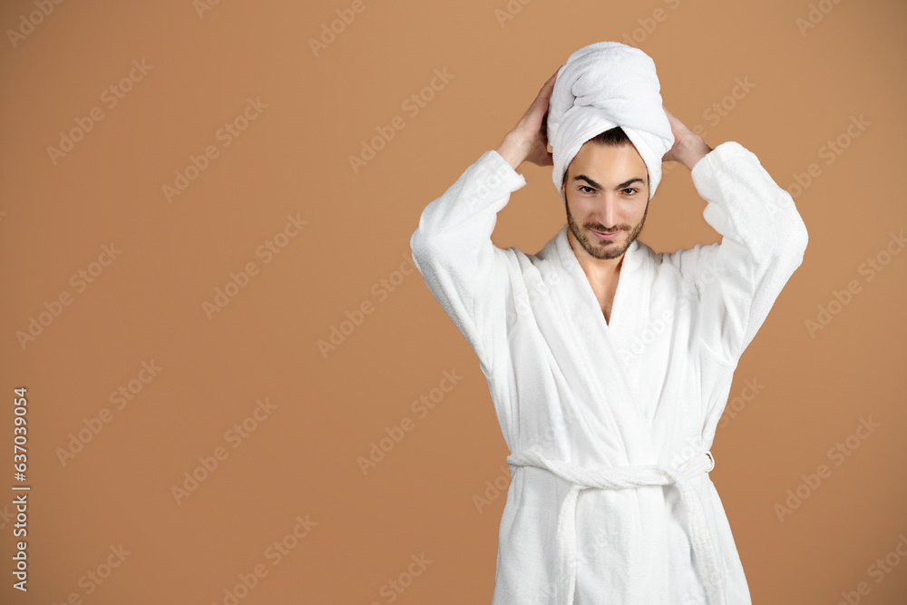 Smiling Hispanic Young Man Touching Towel On Head, Beige Background Smiling Hispanic Young Man Touching Towel On Head, Beige Background