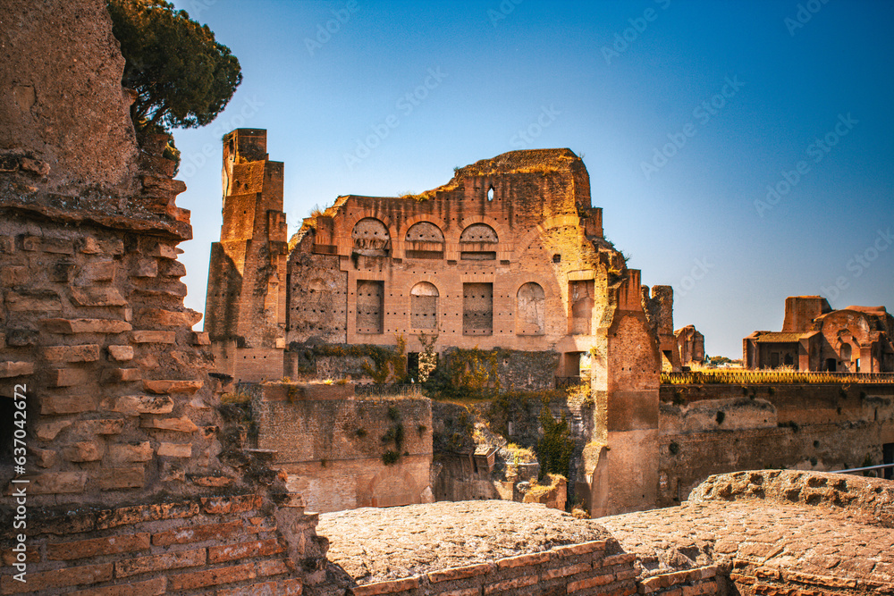 The ruins of a Roman structure bask in the golden sunlight, showcasing arches and the remnants of walls against a serene blue sky, a testament to the architectural prowess of ancient times.