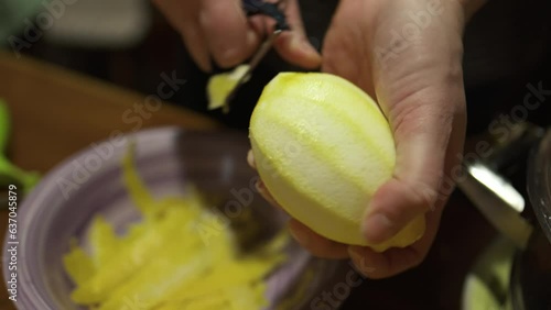 Homemade alcoholic drink limoncello in the home kitchen in the Italian village. Woman peeling lemon skin using a peeler 4K
