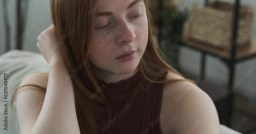 A teenage girl is depicted sitting on a sofa in the living room with a sad and pensive expression. The subdued lighting and the atmosphere of the living room emphasize the somber mood of the scene. A teenage girl is depicted sitting on a sofa in the living room with a sad and pensive expression. The subdued lighting and the atmosphere of the living room emphasize the somber mood of the scene.