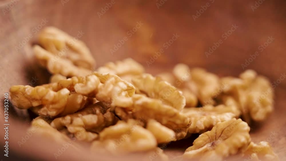 Organic peeled walnut kernels falling into a rustic wooden dish close up. Rotation. Slow motion Organic peeled walnut kernels falling into a rustic wooden dish close up. Rotation. Slow motion