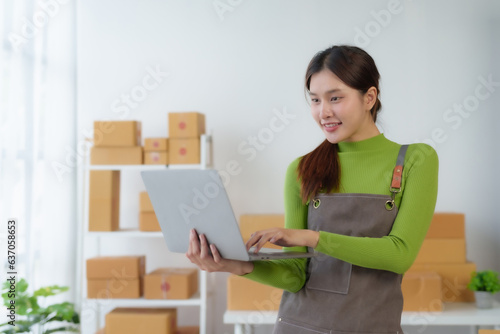 Asian businesswoman starting sme. Owner of a small online business SME Distribution warehouse with boxes SME Online Marketing and product packaging and delivery services. © amnaj