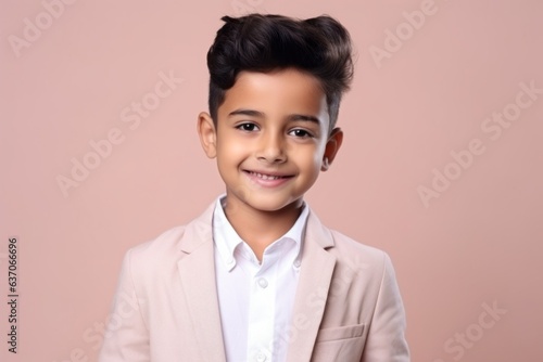 Portrait of a cute little boy in a beige suit on a pink background