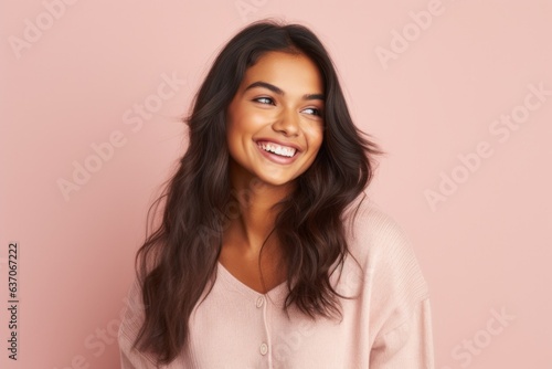 Portrait of a beautiful happy young woman smiling against pink background.