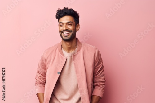 Portrait of a happy young indian man smiling against pink background © Leon Waltz