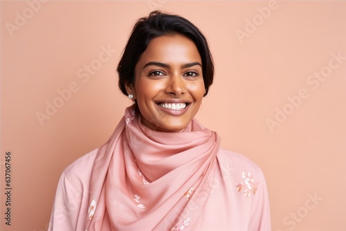 Portrait of a beautiful young woman in a pink scarf on a beige background