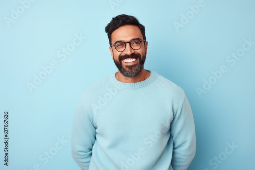 happy indian man with eyeglasses looking at camera over blue background