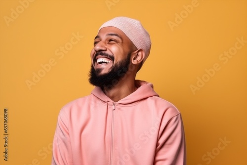 Young african american man wearing a pink hoodie over yellow wall laughing