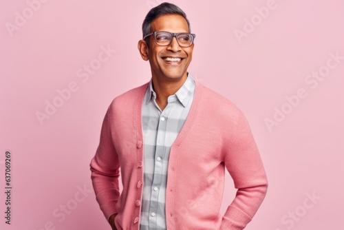 Smiling indian man in eyeglasses standing against pink background © Leon Waltz