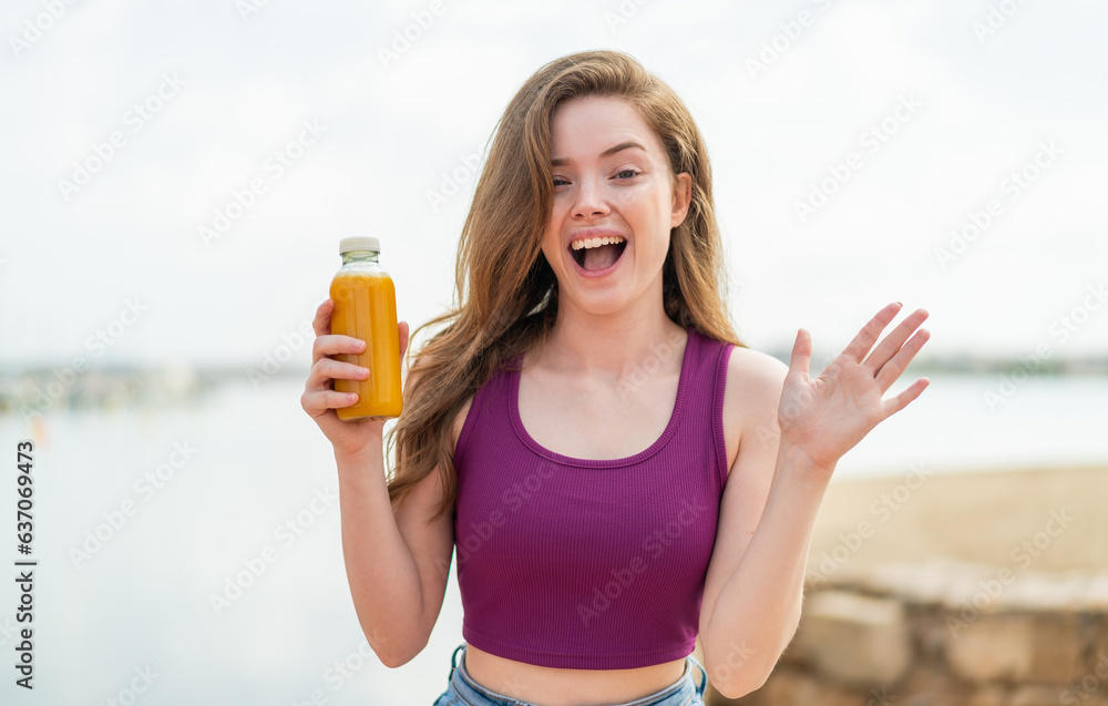 Young redhead girl holding an orange juice at outdoors with shocked facial expression Young redhead girl holding an orange juice at outdoors with shocked facial expression