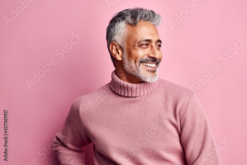 Portrait of a smiling Indian man in a pink sweater on a pink background