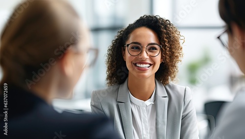 Smiling businesswoman in eyeglasses talking with colleague in office