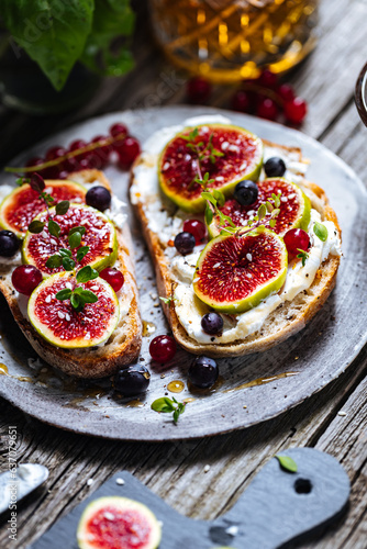 Toast spread with cream cheese, figs, currants and honey. Tasty and healthy brunch. Colourful scene.