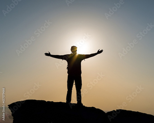 Silhouette of male on the mountain with open arms - Successful hiker exult on the top of the rock - Leadership concept