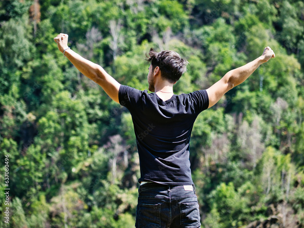 Photo of a man standing in front of a lush green forest Photo of a man standing in front of a lush green forest