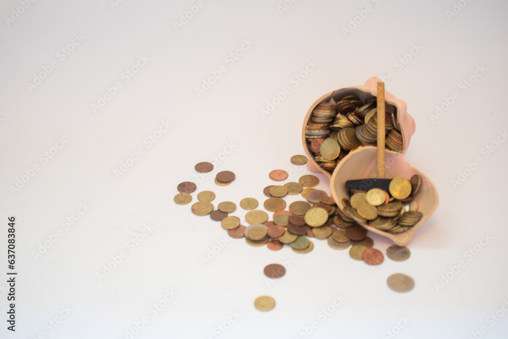 Euro money coins spilling out of a piggy bank on a white background. Savings, inflation, economy concept. Euro money coins spilling out of a piggy bank on a white background. Savings, inflation, economy concept.