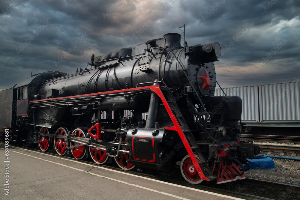 Naklejka premium An old steam locomotive of the early 20th century on the railway track.