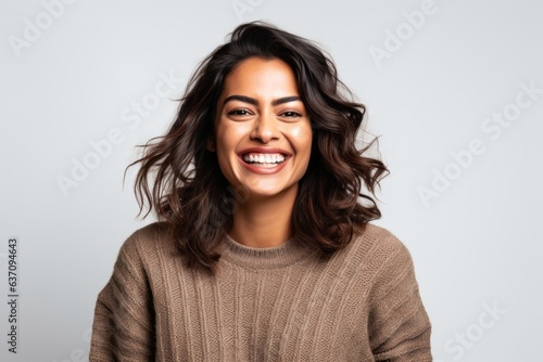 Lifestyle portrait of an Indian woman in her 30s against a white background
