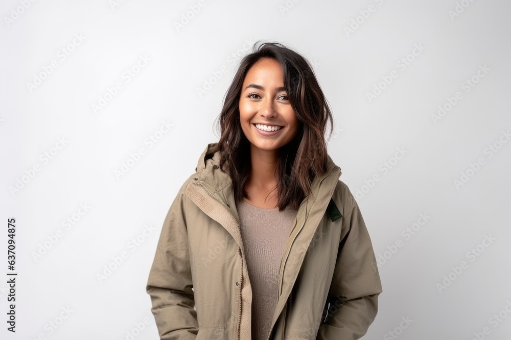 Medium shot portrait of an Indian woman in her 30s wearing a warm parka against a white background Medium shot portrait of an Indian woman in her 30s wearing a warm parka against a white background