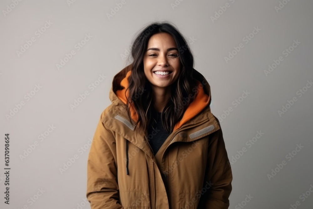 Medium shot portrait of an Indian woman in her 30s wearing a warm parka in a minimalist background Medium shot portrait of an Indian woman in her 30s wearing a warm parka in a minimalist background