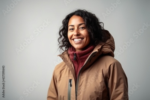 Medium shot portrait of an Indian woman in her 30s wearing a warm parka in a minimalist background © Eber Braun