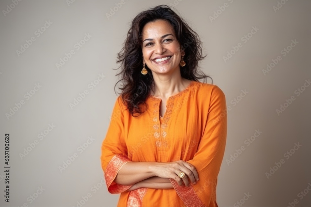 Medium shot portrait of an Indian woman in her 40s wearing salwar kameez in a minimalist background