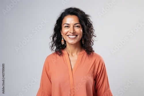 Medium shot portrait of an Indian woman in her 40s wearing salwar kameez in a minimalist background