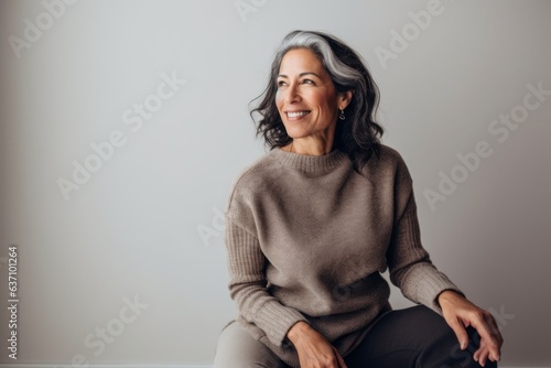 Lifestyle portrait of an Indian woman in her 50s in a minimalist background