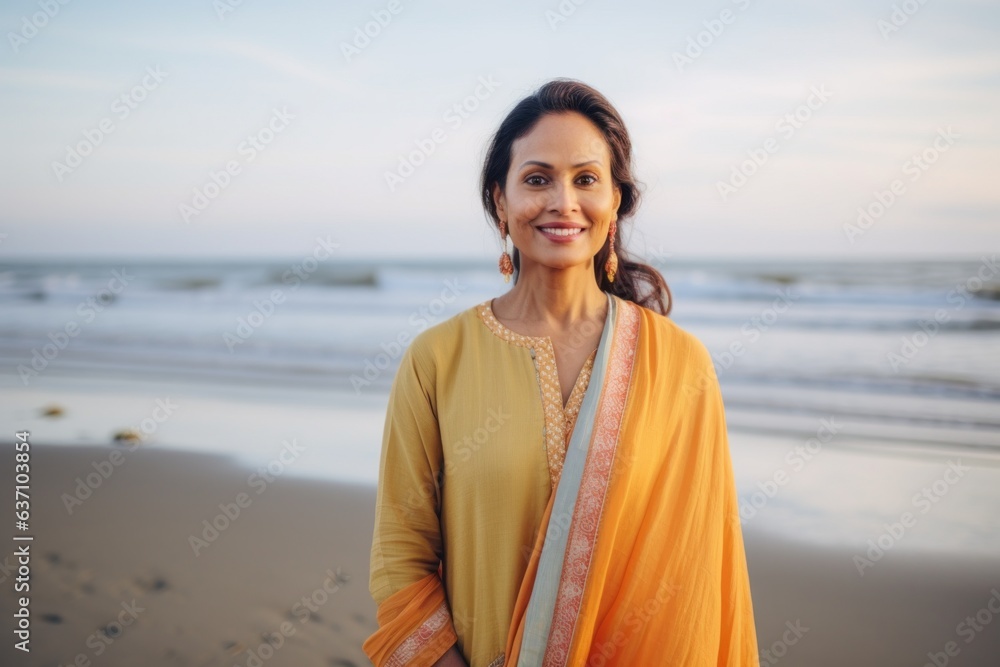 Portrait of smiling mature woman in saree standing on beach at sunset Portrait of smiling mature woman in saree standing on beach at sunset