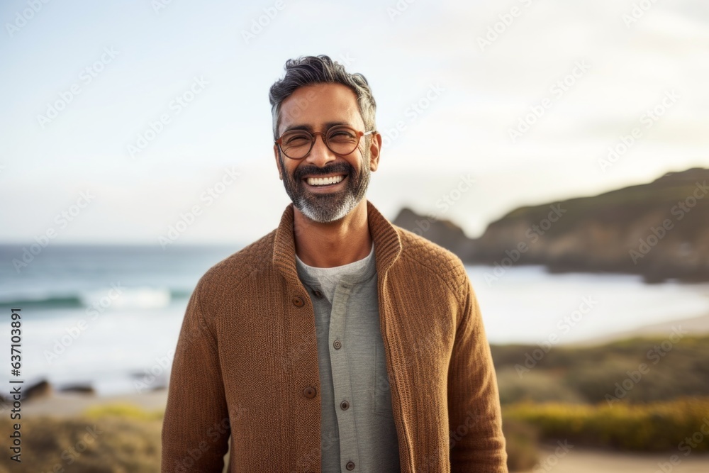 Portrait of smiling mature man with eyeglasses standing on beach