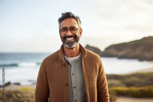Portrait of smiling mature man with eyeglasses standing on beach