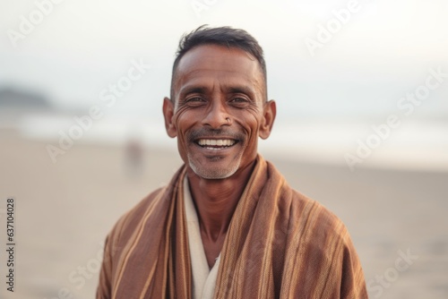 Portrait of smiling Indian man with towel on his shoulders standing on beach