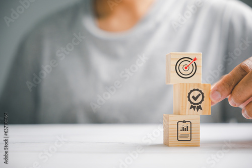 Hand arranging wood blocks to create a strategic stack, aiming for business goals. Conceptual image of business development and success. photo