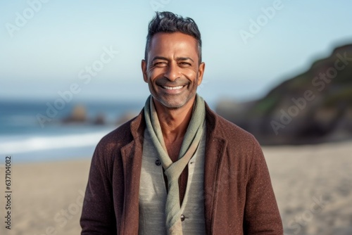 Portrait of handsome middle-aged man smiling at camera on beach