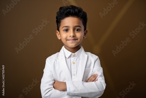 Portrait of a little boy with his arms crossed against brown background
