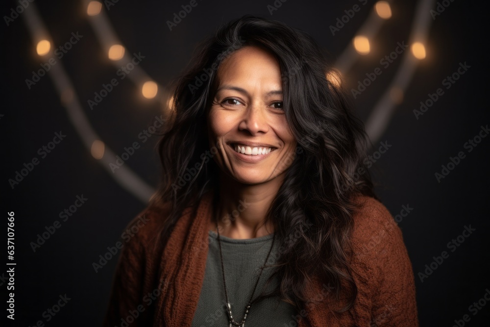 Fototapeta premium Portrait of a beautiful woman smiling at the camera with lights in the background