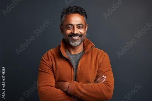 Portrait of a happy Indian man with arms crossed over grey background © Eber Braun