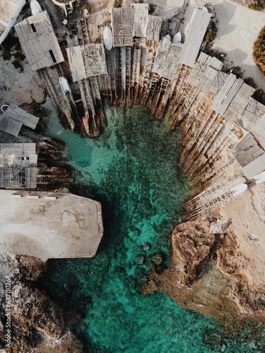 Aerial view of wooden structures on the shore of the bay with bright turquoise water. Formentera.