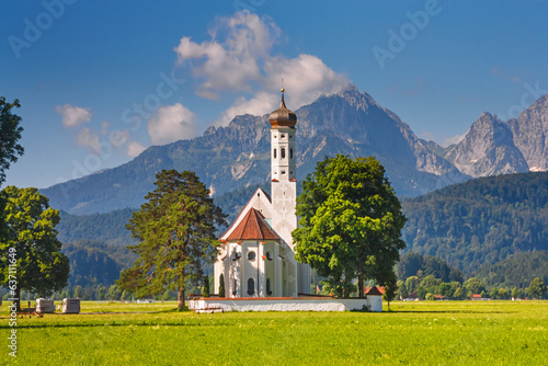 Bavarian landscape - view of the church of St. Coloman on the background of the Alpine mountains in summer day, Germany photo