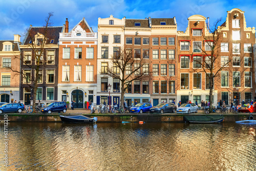 Cityscape on a sunny winter day - view of the houses and the city canal with boats in the historic center of Amsterdam, The Netherlands